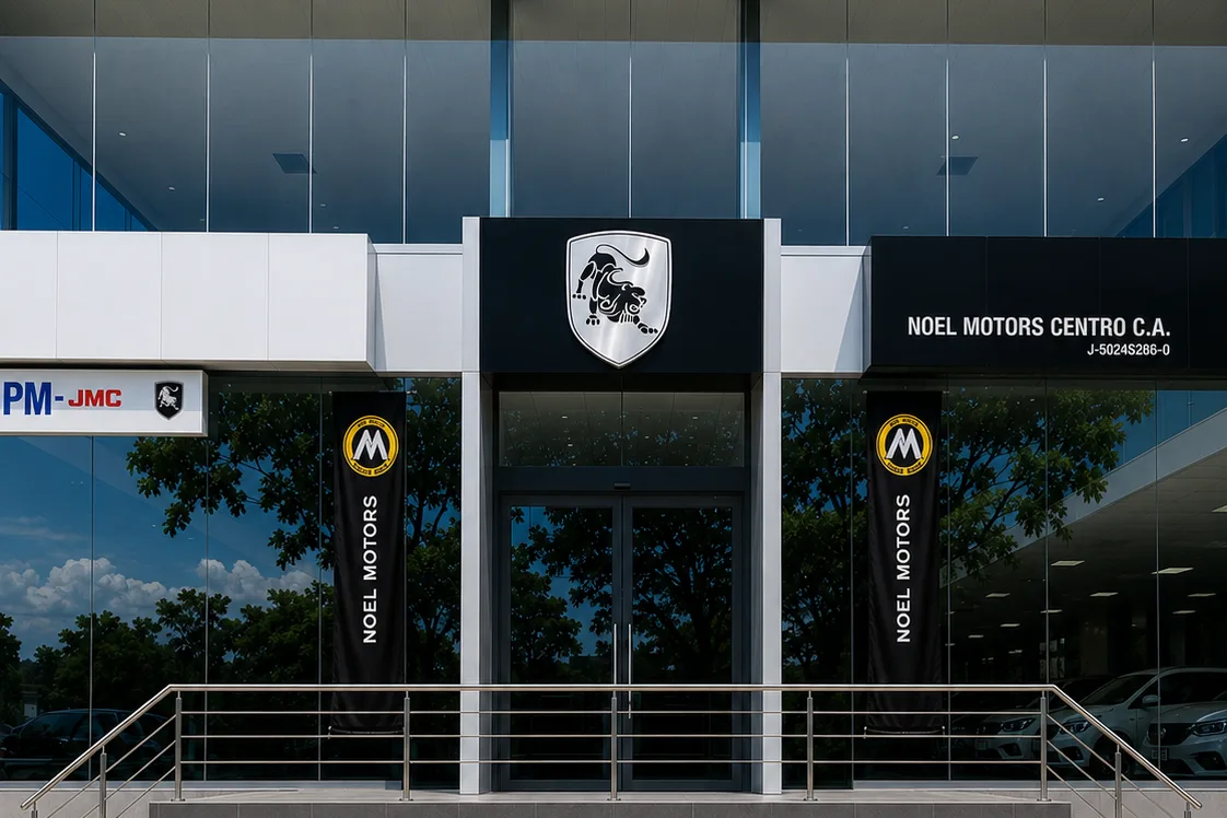 Entrada de Noel Motors Centro: rótulo con el nombre sobre las puertas de vidrio y puestos de estacionamiento para visitantes.